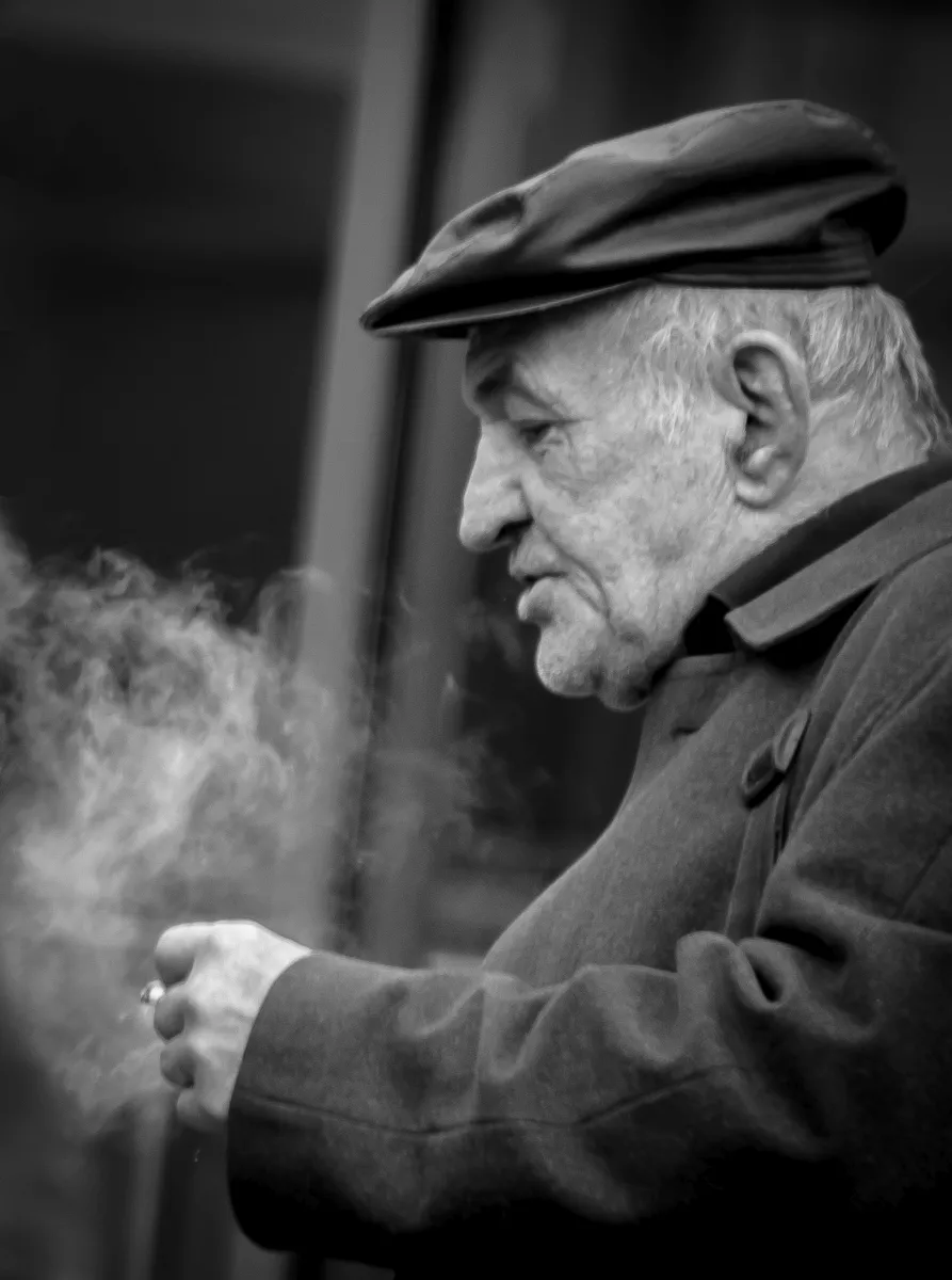 Older man in a flat cap smoking in profile